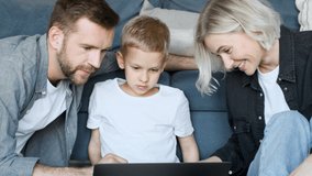 Happy family looking at videos on laptop while kid point at screen and talk smiling