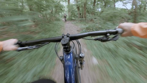 Point of view, action camera, people mountain biking trough tick forest. 