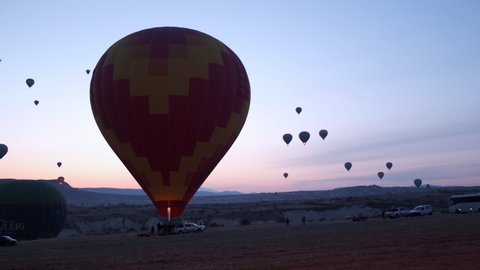 Cappadocia, Turkey - MARCH 25 2021. Hot Air Balloon. Huge Silhouette. Get of Flame Fills with Hot Air. Ready to Take Off. Getting Dark. Beautiful Sunset. Festival. View of Mountains. Romance. 