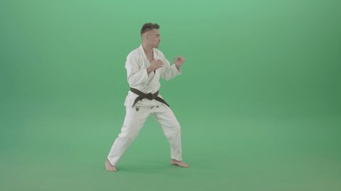 Jujitsu Man training to fight combat. Man in white karate clothes training moves and kicks isolated on green background. Martial arts taekwondo training footage.