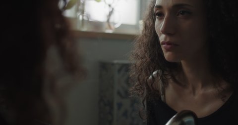 Close up of an insecure woman staring at her reflection in the mirror, feeling lonely and sad. Slow motion, handheld. Video de stock
