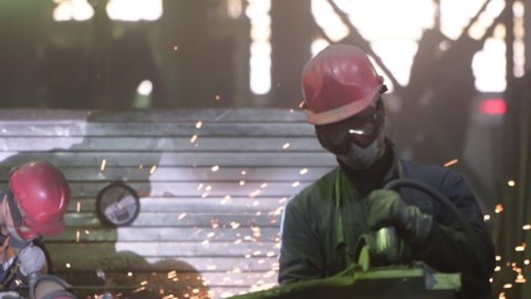 Modern Metal Production Facility. A Laborer is Dealing with Metal Production. Using the Grinding Tool to Scrape off the Excess Metal from the Part. Industrial Metal Production Process. Slow-motion.