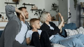 Happy young Caucasian family with kid wave to friends talking during smartphone video call at home slow motion.