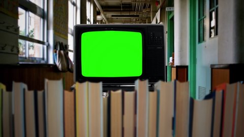 Television In School Green Screen TV Behind Books. Vintage green screen television inside school behind books. Zoom in