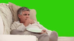 Elderly man eating in front of the tv against a green screen