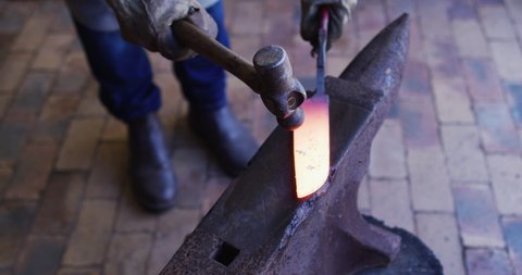 Close up hands of caucasian male knife maker in workshop using oven. independent small business craftsman at work.
