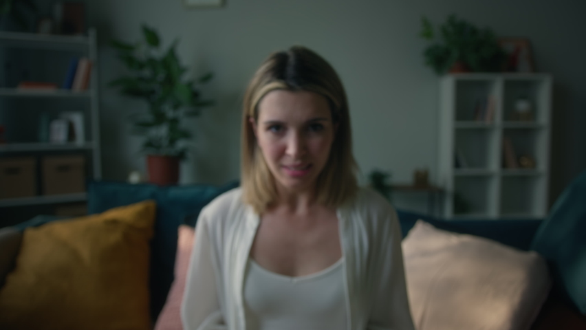 Irritated emotional young woman shouting, portrait of screaming female person sitting on sofa in living room, looking in camera with aggressive view, feeling anger and stress, bad mood. | Shutterstock HD Video #1075241096