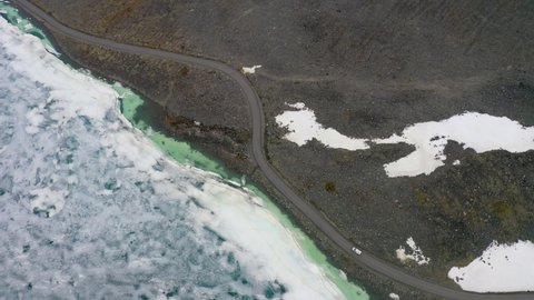 Aerial Lockdown Shot Of Van Moving On Road By Frozen Lake At National Park - Jotunheimen National Park, Norway