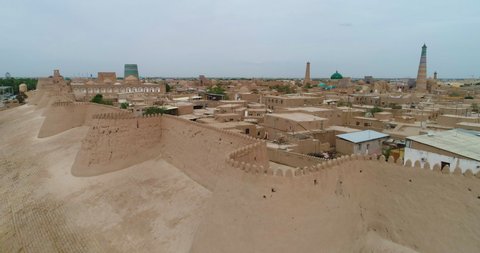 Aerial Forward Shot Of Religious Structures And Houses In Itchan Kala Surrounding Wall Against Clear Sky - Khiva, Uzbekistan