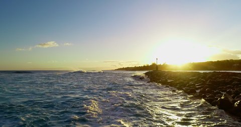 Aerial: Waves Rushing On Groyne In Sea Against Cloudy Sky During Sunset - Kauai, Hawaii