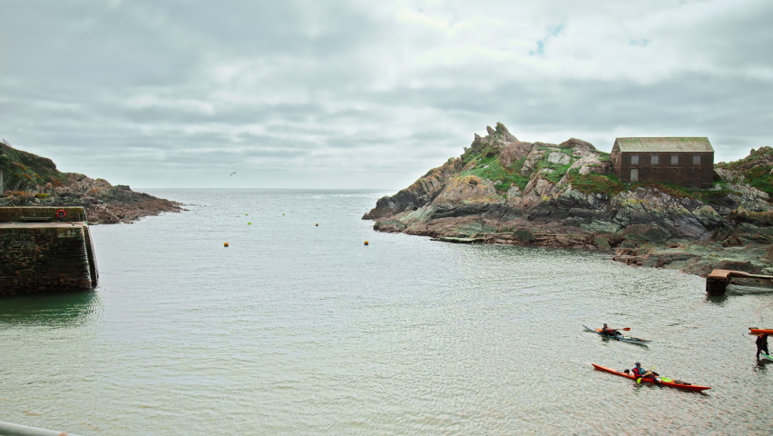 Tourists swiming in kayak by Polperro Harbour and Beach with Chapel Pool, Cornwall, England, UK.