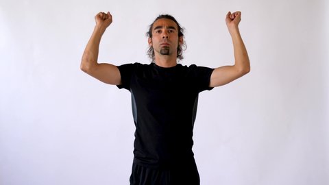 Long Haired Hispanic Man with Goatee Performs Active Wrist Stretch in Front of White Studio Backdrop