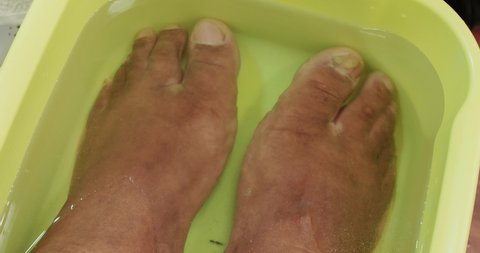 Male feet soaking in warm water to begin with the feet treatment