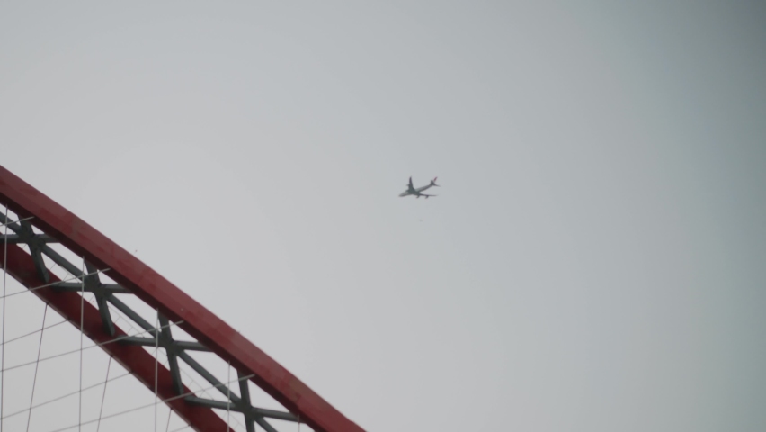 The plane flies over the bridge
