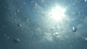 Underwater air Bubbles with sunlight through water surface, natural slow motion under water scene. Air bubbles floating from  the sea bottom up to  water surface - Powered by Shutterstock - Get 15% off with code: PIKWIZARD15