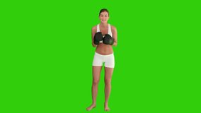 Pretty brown-haired woman with boxing gloves against a green screen
