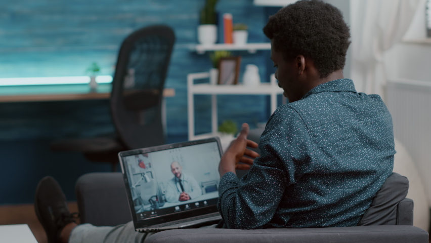 Selective focus on african american patient at home looking for medical help from doctor via online intenet telehealth consultation with family doctor. Health care checkup via video virtual conference