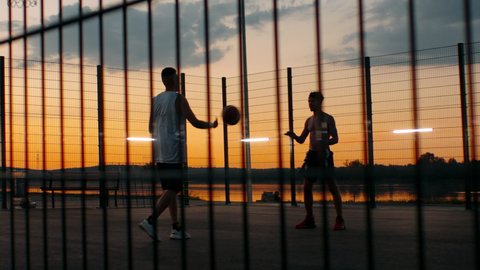 HANDHELD Black African American friends playing 1 on 1 streetball on scenic outdoor court in the evening. High quality 4k footageの動画素材