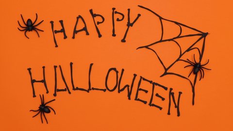 Happy Halloween. Black spiders crawl across the orange background and black letters appear. Stop motion.4k