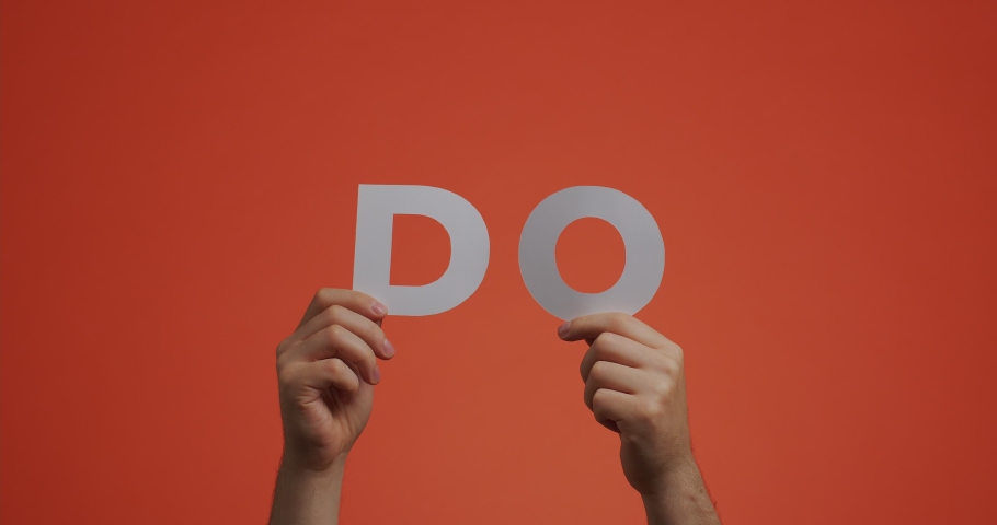 Hands showing DO sign word of english language. Man shows motivational phrase made of carved paper for blog