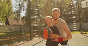 Basketball players sport happy family father and son training with ball on basketball court. Dad help kid scoring hoop