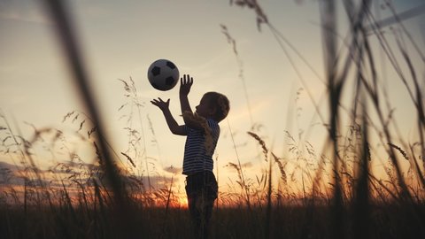 Childhood dream. boy play soccer ball in the park silhouette. happy family kid fun dream concept. kid boy play on the field silhouette at sunset carries a soccer ball. baby winner