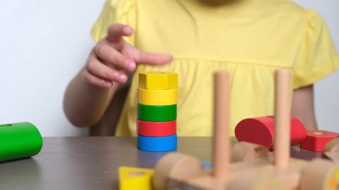 4K child playing wooden train with colorful geometric shapes. Educational logical toys for children. 