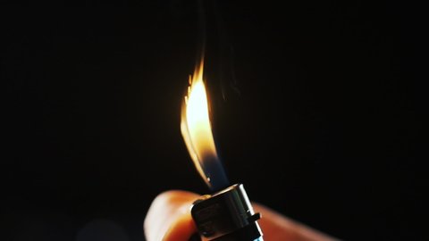 Male hand with a gas lighter. The man makes fire. slow motion footage. Lighter is being lighten up. thumb spin the lighter wheel it throws sparks up then it catches fire in slow motion