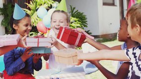 Animation of gold confetti over diverse happy children giving girl presents at party. celebration, birthday, party, childhood and event concept digitally generated video.