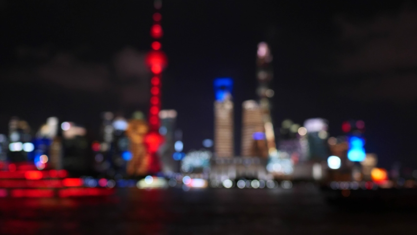 Defocused 4k footage of Shanghai cityscape at night, sightseeing tourism ship sailing in Huangpu river with Shanghai landmarks background, 4k b roll footage.