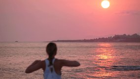 Big sun. Blurred defocus silhouette of girl on background of dawn or sunset. Girl raise, lowers her hands, waves her hands. Concept of early rise, morning, sports. Girl goes for sports at dawn Video