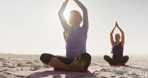 Animation of text good vibes only, in purple and white, over women doing yoga on beach. positive feelings and wellbeing, social media concept, digitally generated video.