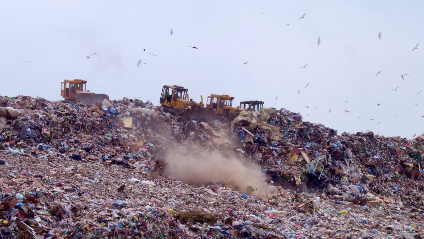 Excavators clear the landfill with household solid waste. The concept of sorting garbage and recycling it into recycled materials. Plenty of birds above the landfill. High quality. 4k footage. | Shutterstock HD Video #1075320449