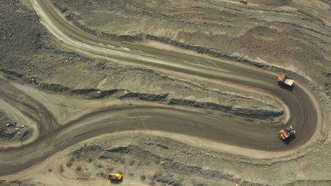 A large quarry where iron ore is extracted. Dump trucks and excavators work inside the quarry. Timelapse.