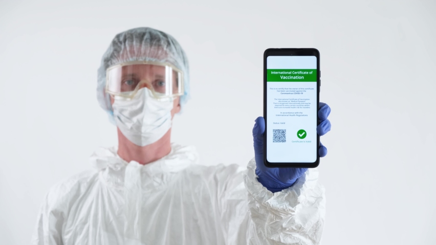 Doctor in Protective Suit Showing a Certificate of Vaccination on a Mobile Phone. - Powered by Shutterstock - Get 15% off with code: PIKWIZARD15
