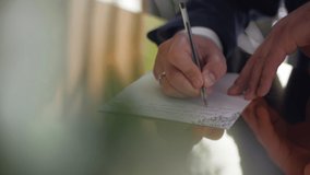 A close-up shot of men's hands writing on a piece of paper. A man in a suit writes a letter sitting at a table. - Powered by Shutterstock - Get 15% off with code: PIKWIZARD15