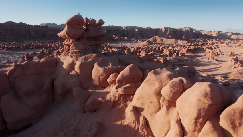 Aerial panoramic view of popular tourists attraction Goblin valley in golden sunrise light. Drone flying low above ancient weird hoodoo formations at empty nature park. USA Utah travel background 4K