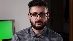 Young bearded business man with glasses talking to the camera and recording a video blog