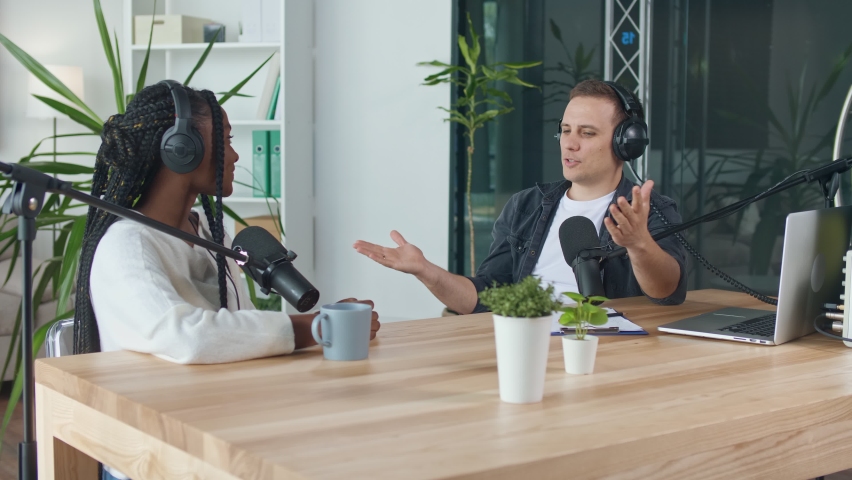 A Male Presenter Communicates with a Guest, an African American, During a Radio Broadcast at a Table in a Recording Studio, Broadcasts a Live Radio Interview With Spbd. Male Host Sharing Content. | Shutterstock HD Video #1075343477