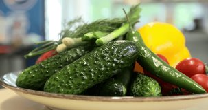 Rotating vegetables. Video of freshly washed vegetables and greens: tomatoes, sweet pepper, green onions and dill spinning on a round white plate.