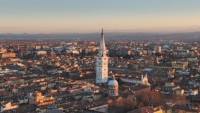 city of modena aerial view at sunset,drone flying backwards over downtown showing ghirlandina bell tower,emilia romagna italy 4k