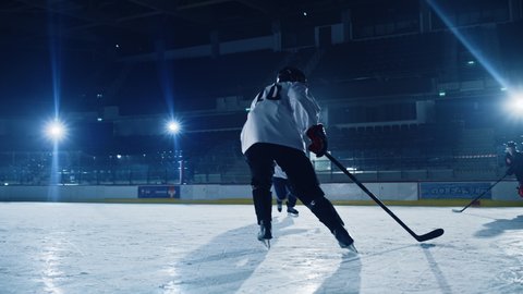 Ice Hockey Rink Arena: Professional Forward Player Breaks Defense, Hitting Puck with Stick Scores Goal, Goalie Missed it. Team Celebrates Victory. Cinematic Flares, Slow Motion Tracking Pan Left Shot
