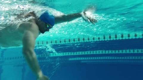 Underwater Shot: Fit Muscular Swimmer doing Laps in Swimming Pool. Handsome Professional Athlete swims at Great Speed- Ready To Set World Championship Record. Stylish Medium Shot