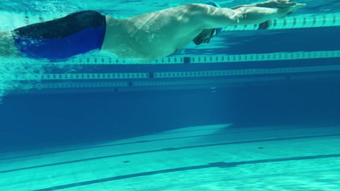 Underwater Shot: Fit Muscular Swimmer Jumps, Dives into Swimming Pool. handsome Professional Athlete swims at Great Speed- Ready To Set World Championship Record. Stylish Medium Shot