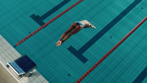 Beautiful Female Swimmer Diving in Swimming Pool. Professional Athlete Gracefully Jumps. Person Determined to Win Championship. Cinematic Static Lock Shot. Slow Motion, Stylish Colors, Artistic Aerial