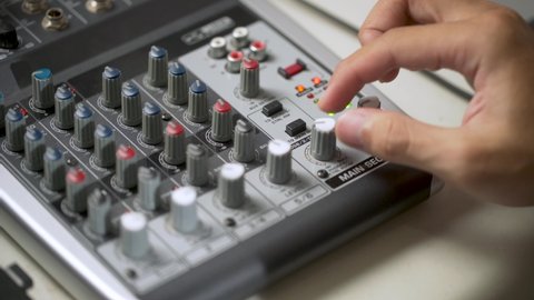 young man hand setting up the audio mixing console, audio mixer controller or board audio mixer