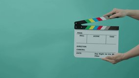 Movie slate or clapperboard hitting. Close up hand holding empty film slate and clapping it. LED colorful blue pink background studio. Open and close film slate for video production. film production.