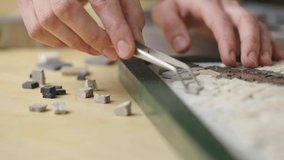 Male hands create mosaics pattern using tweezers and small pieces of granite stone. Master making handicraft in creative workshop. Interesting hobby, art, artwork. Close up. Slow motion ready 59.94fps - Powered by Shutterstock - Get 15% off with code: PIKWIZARD15