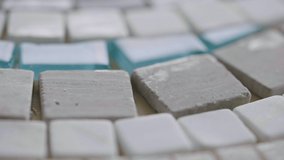 Detailed macro shot of a tiled natural stone mosaic. White mosaic of small stone tiles in an art studio. Close up. Slow motion ready 59.94fps. - Powered by Shutterstock - Get 15% off with code: PIKWIZARD15