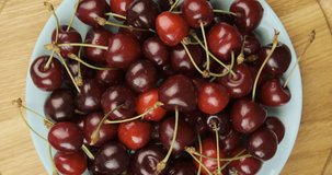 Ripe red cherries on round plate. Summer fresh berries. Rotating turntable clockwise shot. Rotating video. 